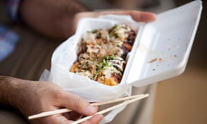 Takoyaki octopus balls on a polystyrene tray.