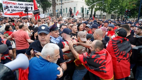 Protesters in Tirana hold up banners and shout in protest over the proposed development in Albania