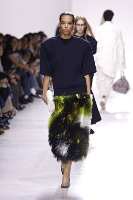 A model walks down the catwalk at Bottega Veneta spring/summer 2026 wearing a printed skirt and black top with big shoulder pads.
