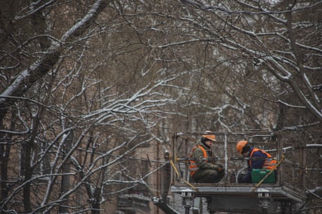 City workers repair damaged electrical wires amid the snowfall in Odesa.