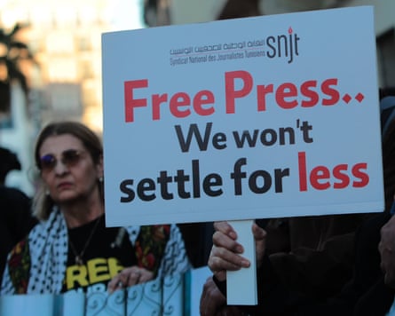 A protester holding a motion reference 'Free press, we won't settee for less'