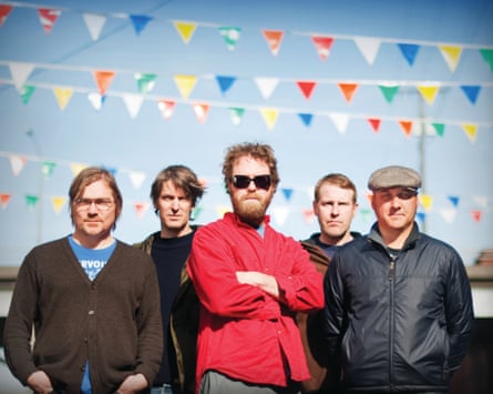 Les cinq membres du groupe Pavement photographiés devant des guirlandes de banderoles de carnaval