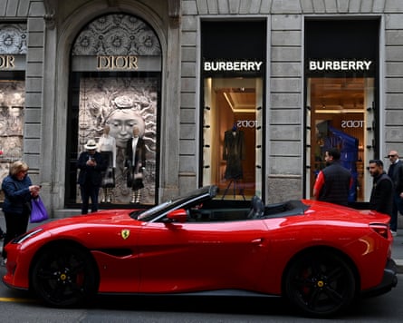 A red Ferrari is parked in front of Dior and Burberry boutiques in Via Monte Napoleone, an upmarket shopping street in Milan
