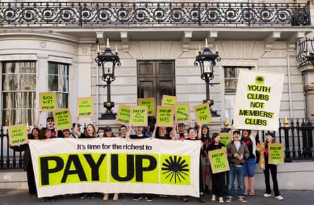 Protesters holding banners and placards with slogans including 'It's time for the richest to pay up', outside a white Portland stone building with Palladian facade