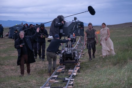 The director walks with the crew and actors during filming on a hillside