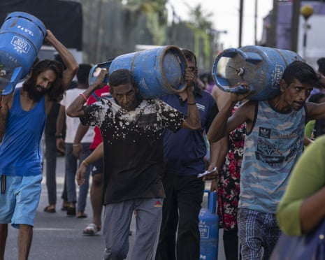 People carry gas cylinders bought at a distribution centre in Colombo