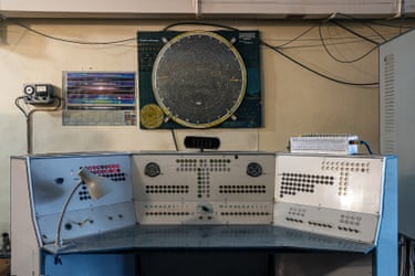 A map of space over a control panel with rows of small lights, some of which are glowing red