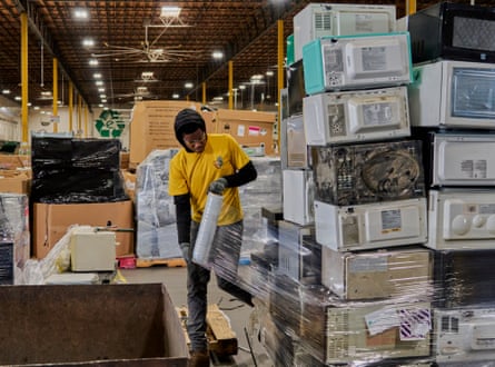 An employee at the Electronics Recyclers International facility in Fresno, California plastic-wraps microwaves