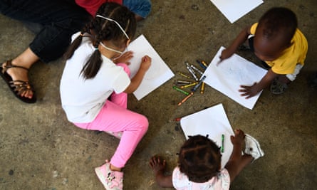 کودکان در حالی که در پناهگاهی در تیجوانا با افرادی که در سال 2022 به دنبال پناهندگی هستند زندگی می کنند، با مداد رنگی نقاشی می کنند.