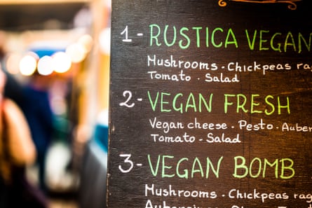 A restaurant sign in the street offering vegan dishes.