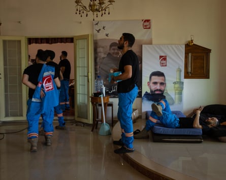 People in blue paramedic uniforms in front of posters of former colleagues