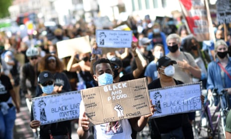 Protesters wearing protective face coverings hold placards as they march down Park Lane in support of the Black Lives Matter movement in London on 5 July