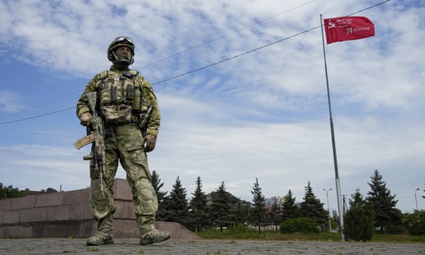 A Russian soldier guards an area at the Alley of Glory in the Ukrainian city of Kherson, which was captured in March