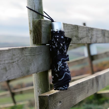 Folded-up umbrella hooked to a fence post in the sun