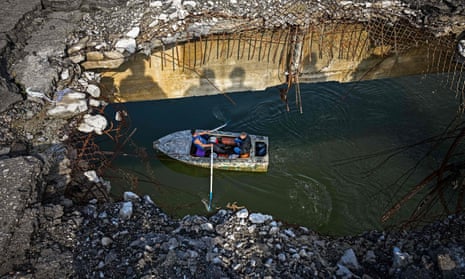 Residents cross the Donets river on a small boat viewed from the air next to a destroyed bridge east of Kharkiv