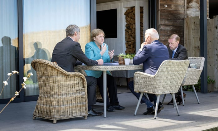 Biden and Merkel during a meeting with their advisers at an outdoor table.