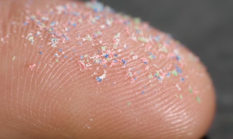 Close up de uma ponta de dedo coberta de microplásticos