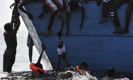 People try to pull a child out of the water as they wait to be rescued by a boat operated by the NGO Proactiva Open Arms in waters off Libya in October 2016.