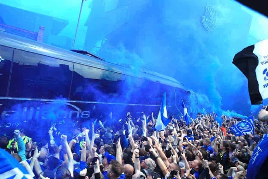 Everton fans light blue smoke flares as they welcome their team bus.