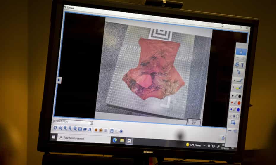 Prosecutor Linda Dunikoski shows a photo of Ahmaud Arbery’s bloody T-shirt with a large hole in it.