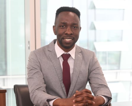 ‘You feel obligated’: African workers on the pain – and pride – of the ‘black tax’ Mangwanya, wearing a suit and tie, sits at a desk