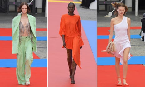 Three models in Stella McCartney’s spring/summer 2023 womenswear designs, including a pastel green trouser suit worn with a fringed top, a vermillion dress and a pale pink one-shoulder dress worn with sandals