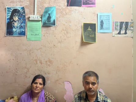 Two indian people sitting beneath seven posters stuck to a wall