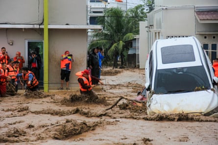 Rescuers brave floodwaters by holding a rope in their effort to evacuate residents trapped in their houses in Padang, West Sumatra province on 27 November.