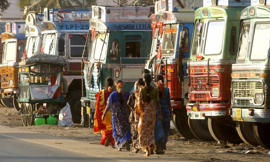 Indian sex workers walk past a row of parked trucks at a truck halt point along a national highway in Nelamangala