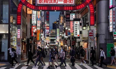 Commuters walk toward a railway station in front of an entrance to Kabukicho in Tokyo