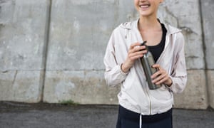 Smiling young woman putting her lid on her water bottle after taking a sip of water