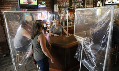 FILE - Sheila Kelly, owner of Powell's Steamer Co. & Pub, center, stands behind makeshift barriers as she helps patrons at her restaurant in the El Dorado County town of Placerville, Calif., Wednesday, May 13, 2020. El Dorado County was one of the first counties to win approval from the state to reopen for dining-in. California is creating roving "strike teams" drawn from seven state agencies that will enforce state guidelines designed to slow the spread of the coronavirus, Gov. Gavin Newsom said Wednesday, July 1, 2020. The Democratic governor on Wednesday broadened restrictions across much of the state on bars, indoor dining, movie theaters and gambling card rooms among others where he said holiday weekend crowds would be particularly vulnerable. (AP Photo/Rich Pedroncelli, File)