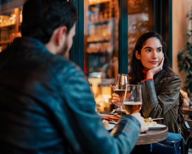 A woman looks away while dining with a partner at a restaurant