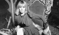 Anita Pallenberg in the 60s/70s sitting powerfully in a throne-like chair looking straight to camera