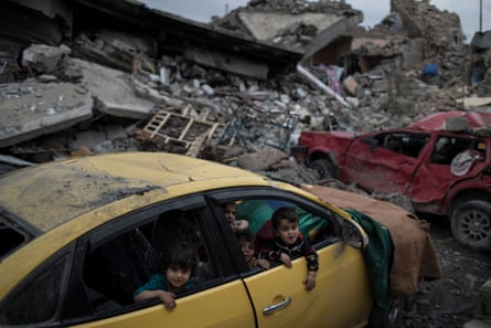 Children play inside a damaged car in a neighborhood recently retaken by Iraqi security forces.