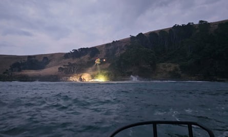 A helicopter shines a light on a boat that has run aground