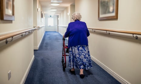 Senior Woman with Walker in a Care HomeA senior woman walking down a corridor with the assistance of a walker. view from rear