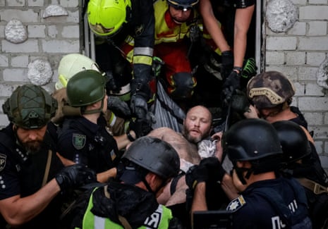 Rescuers and police officers carry a man rescued from debris at the site of an apartment building hit by a Russian drone strike in Kharkiv.