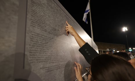 Family members search for names of relatives at a monument during the lighting of the memorial candles.