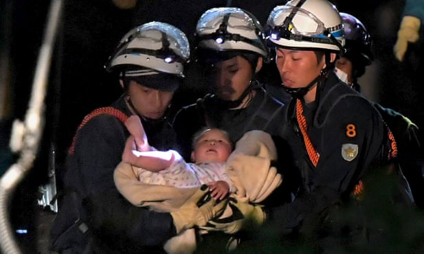 A baby is carried away by rescue workers in Mashiki town.