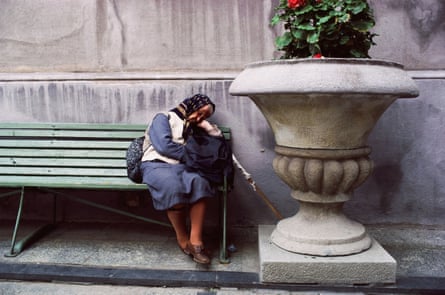 Eine ältere Frau schläft auf einer Bank
