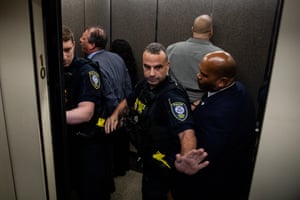 police stand near handcuffed men facing the walls inside an elevator