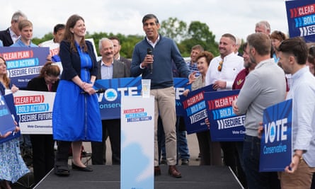 Prime minister speaks at a football club to a crowd of people hold pro-conservative campaign signs.