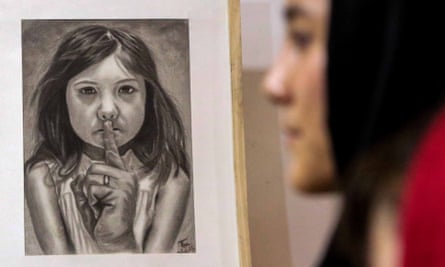 A woman walks past artwork showing a girl being silenced
