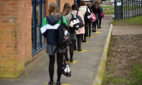 Children line up on distance markers to enter school
