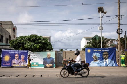 A motorcyclist drives passes election billboards.