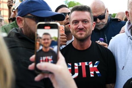 A person takes a photo of Tommy Robinson in a crowd