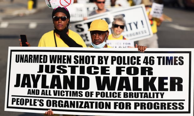 People wearing yellow t-shirts marching. Some of them are holding placards.