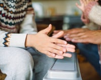 Family warming hands at home over a domestic portable radiator/heater in cold winterEnergy crisis concept