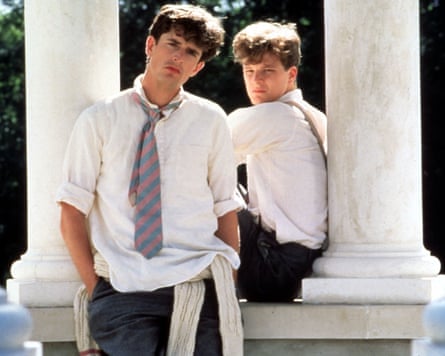Two schoolboys, scowling, lounge against classical marble pillars in the sunshine